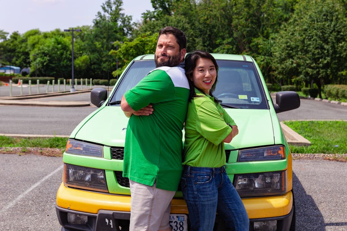 DoodyCalls franchise owners standing back to back in front of DoodyCalls truck