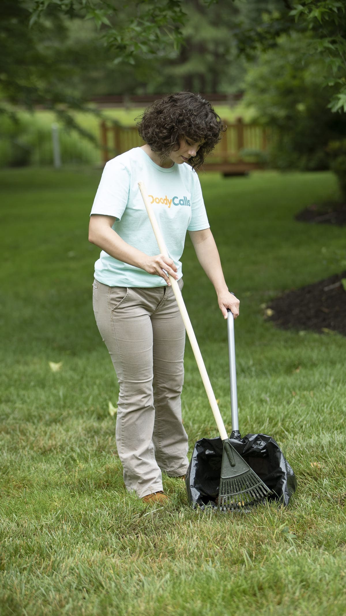 Technician scooping poop from yard with tools