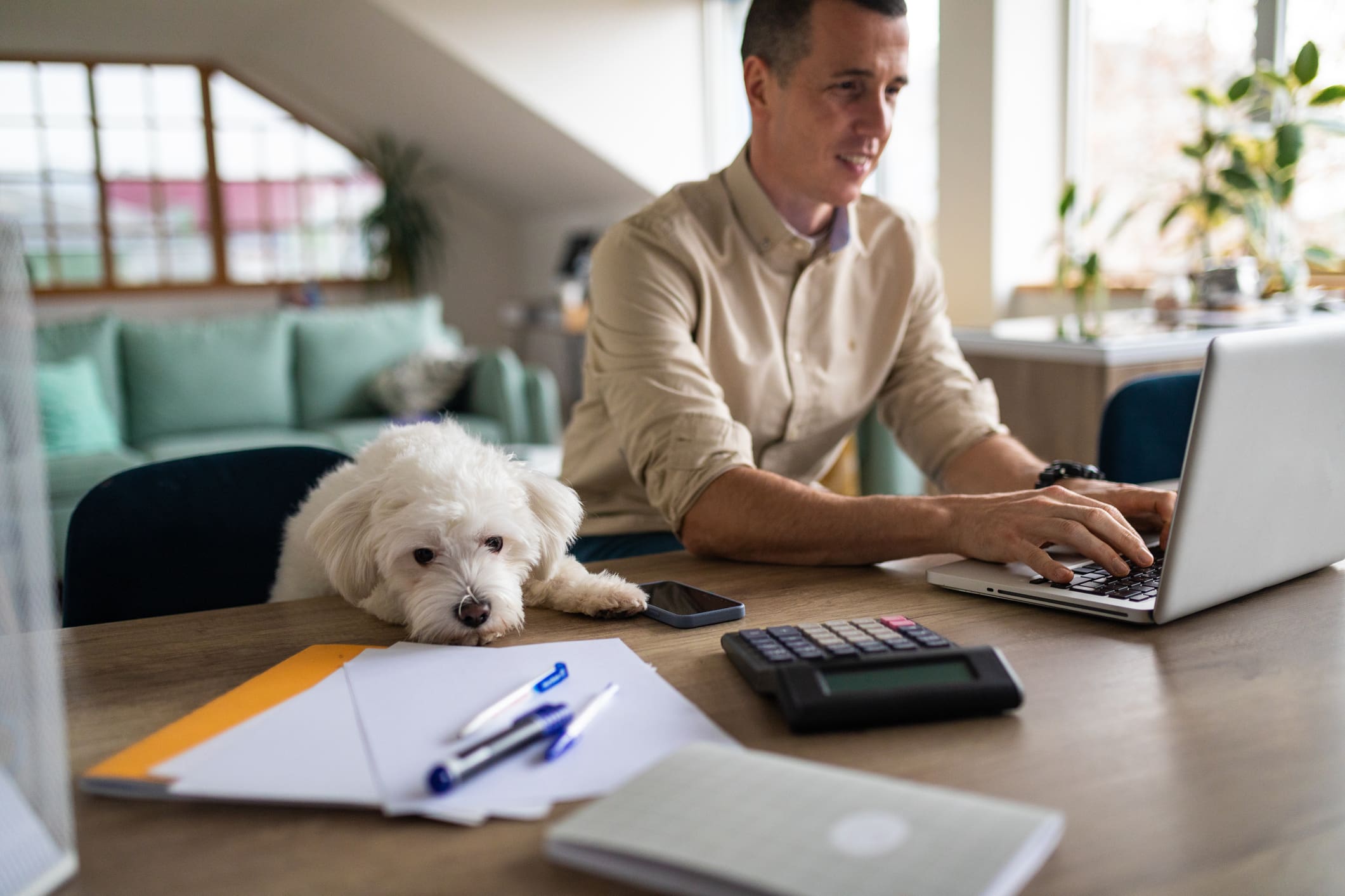 Man looking at computer with dog sitting next to him