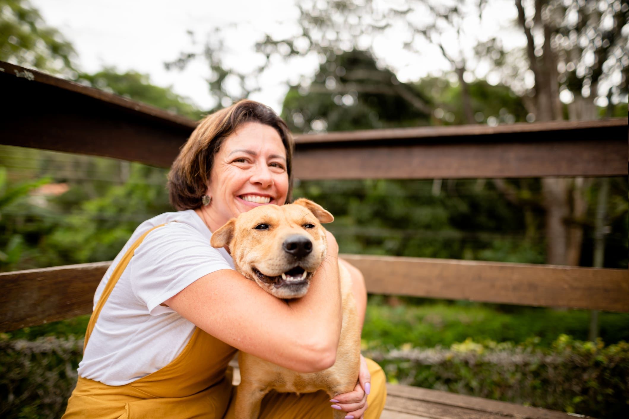 Smiling woman hugging her dog outside in her yard