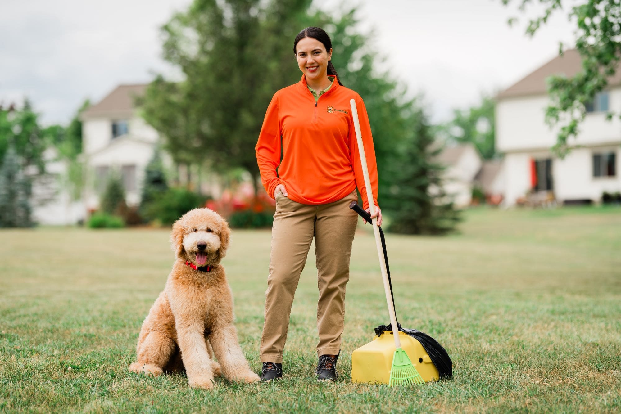 Beginner franchise owner standing in yard with dog wearing DoodyCalls uniform.