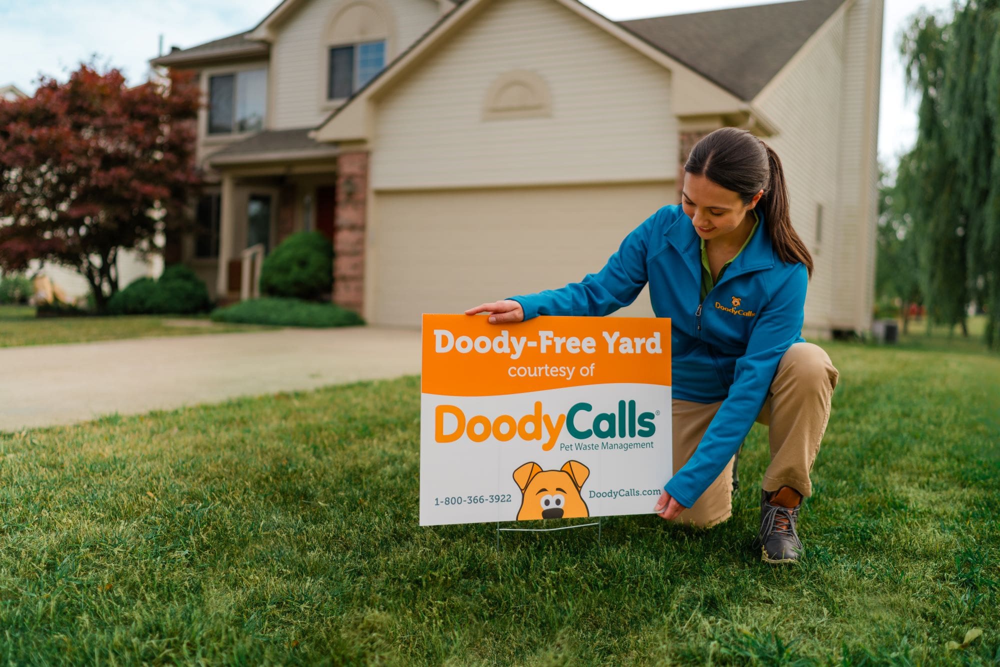 DoodyCalls pet care business owner putting a yard sign in a front yard.